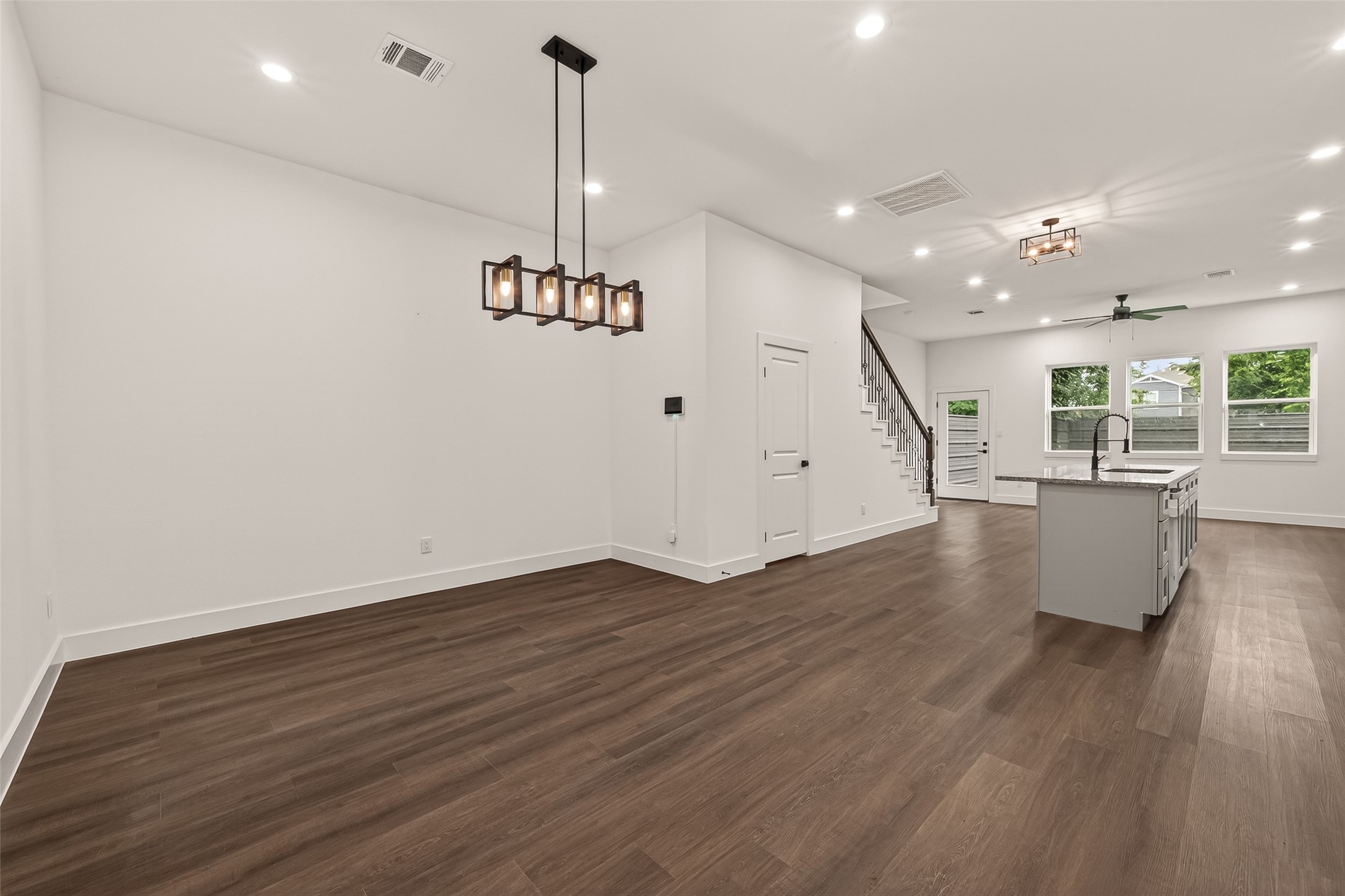 6808 Madrid Street Houston, TX 77021 - Photo 6 of 31 This open-concept living space features elegant engineer wood flooring, modern light fixtures, and a sleek kitchen island. The area is well-lit with recessed lighting and large windows, and there's easy access to the staircase.
