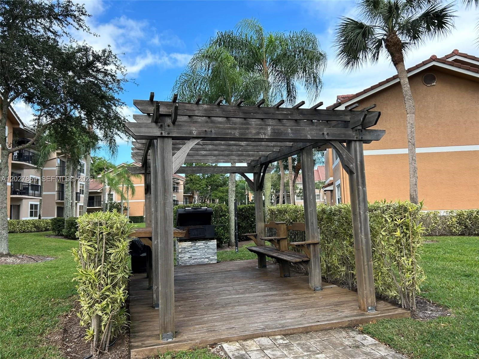 8761 Wiles Road, Unit 206 Coral Springs, FL 33067 - Photo 21 of 26 a view of a patio with table and chairs potted plants and palm trees