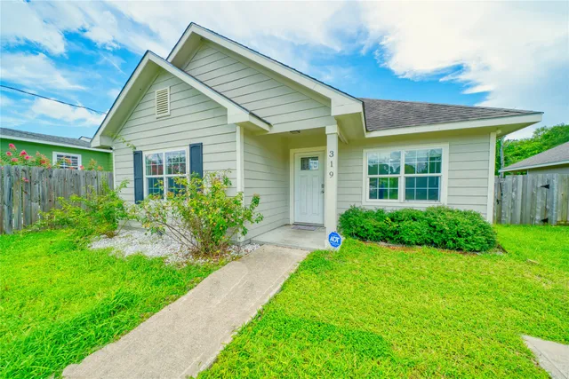 a view of house with a yard and potted plants