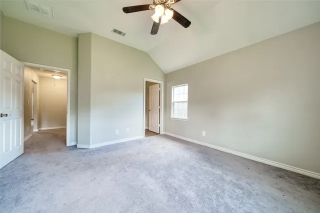 an empty room with chandelier fan and windows