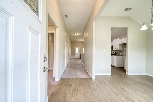 a view of a hallway with wooden floor and a bathroom