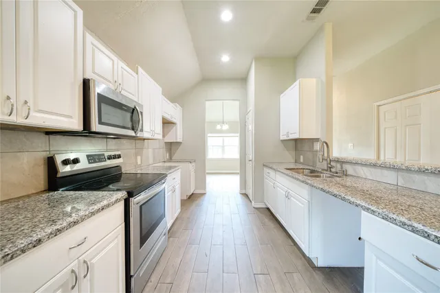 a large kitchen with stainless steel appliances granite countertop wooden cabinets granite counter tops and a stove
