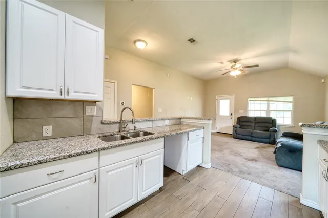 a kitchen with granite countertop a sink cabinets and wooden floor
