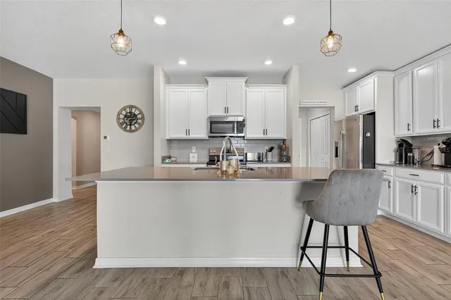 a large kitchen with stainless steel appliances granite countertop a stove a refrigerator a oven a sink a dining table and chairs with wooden floor