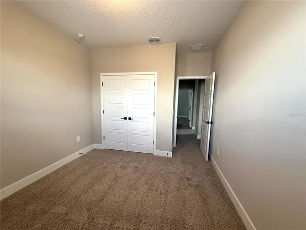 a view of an empty room with closet and a window