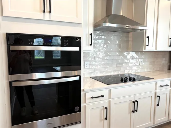 a kitchen with white cabinets and black appliances