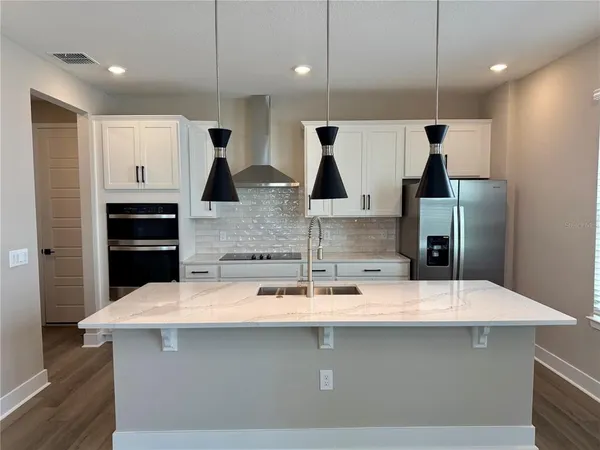 a kitchen with stainless steel appliances a sink a microwave a refrigerator and white cabinets