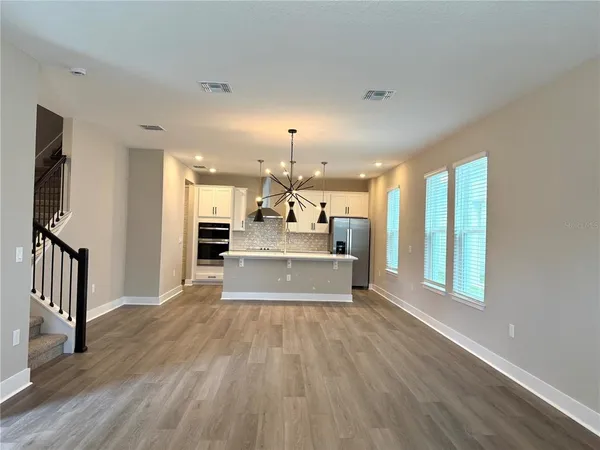 a view of a kitchen with kitchen island wooden floor and stainless steel appliances