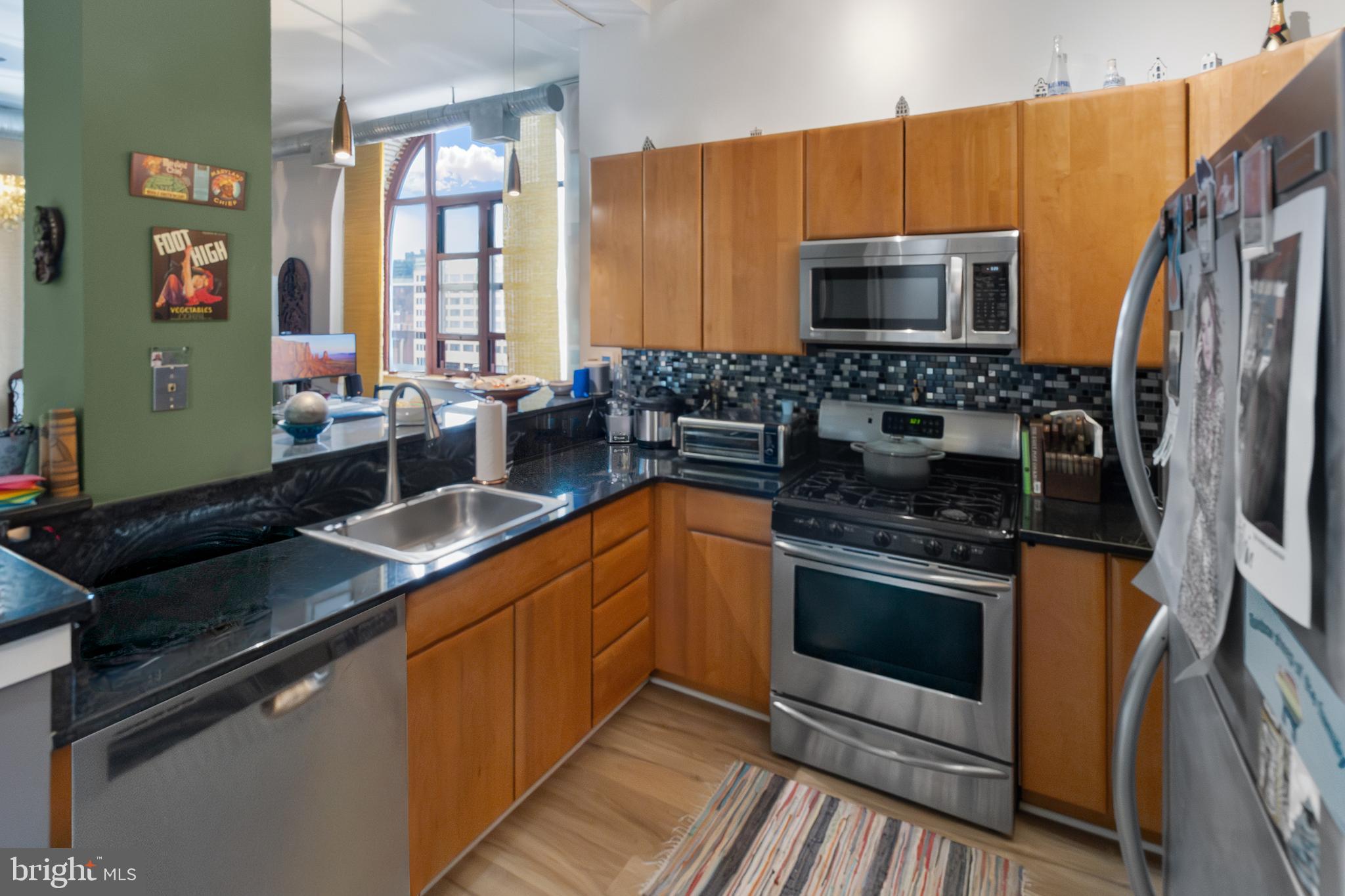 22 South Howard Street, Unit R503 Baltimore, MD 21201 - Photo 10 of 29 a kitchen with stainless steel appliances granite countertop a stove microwave and sink