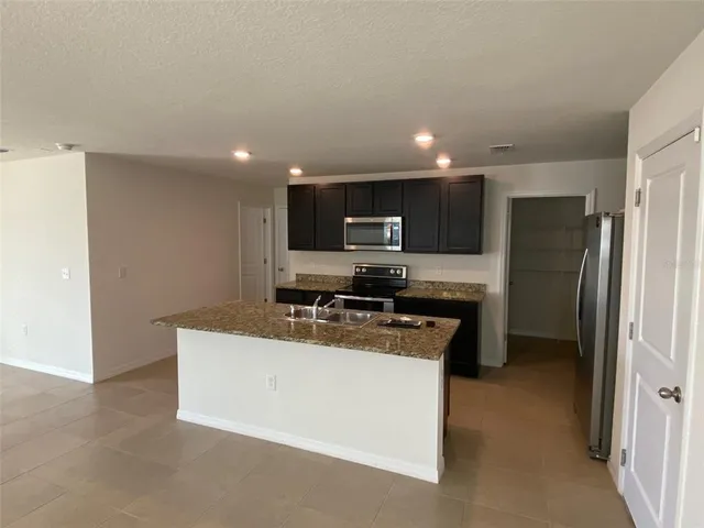a kitchen with kitchen island a refrigerator sink a stove a microwave and cabinets