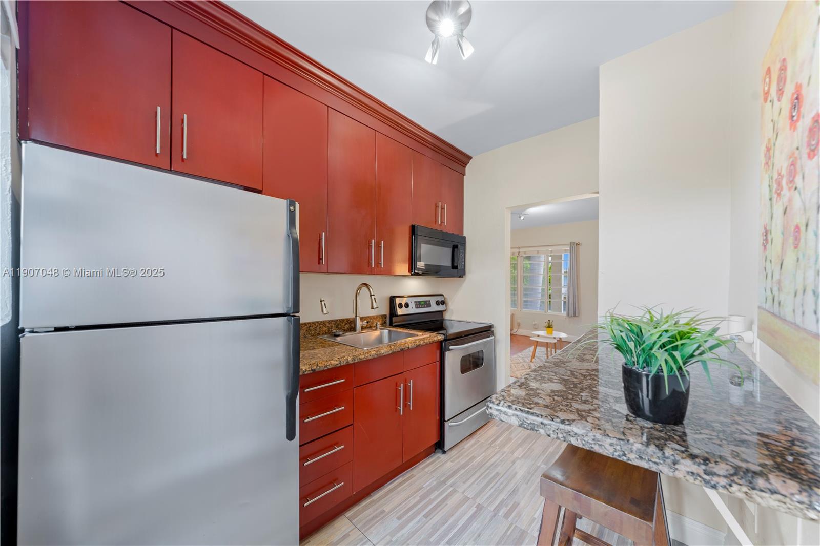 1241 14th Street, Unit 11 Miami Beach, FL 33139 - Photo 11 of 20 a kitchen with stainless steel appliances granite countertop a refrigerator a stove a sink dishwasher and a refrigerator with wooden floor