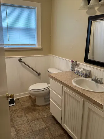 a bathroom with a granite countertop toilet sink and mirror
