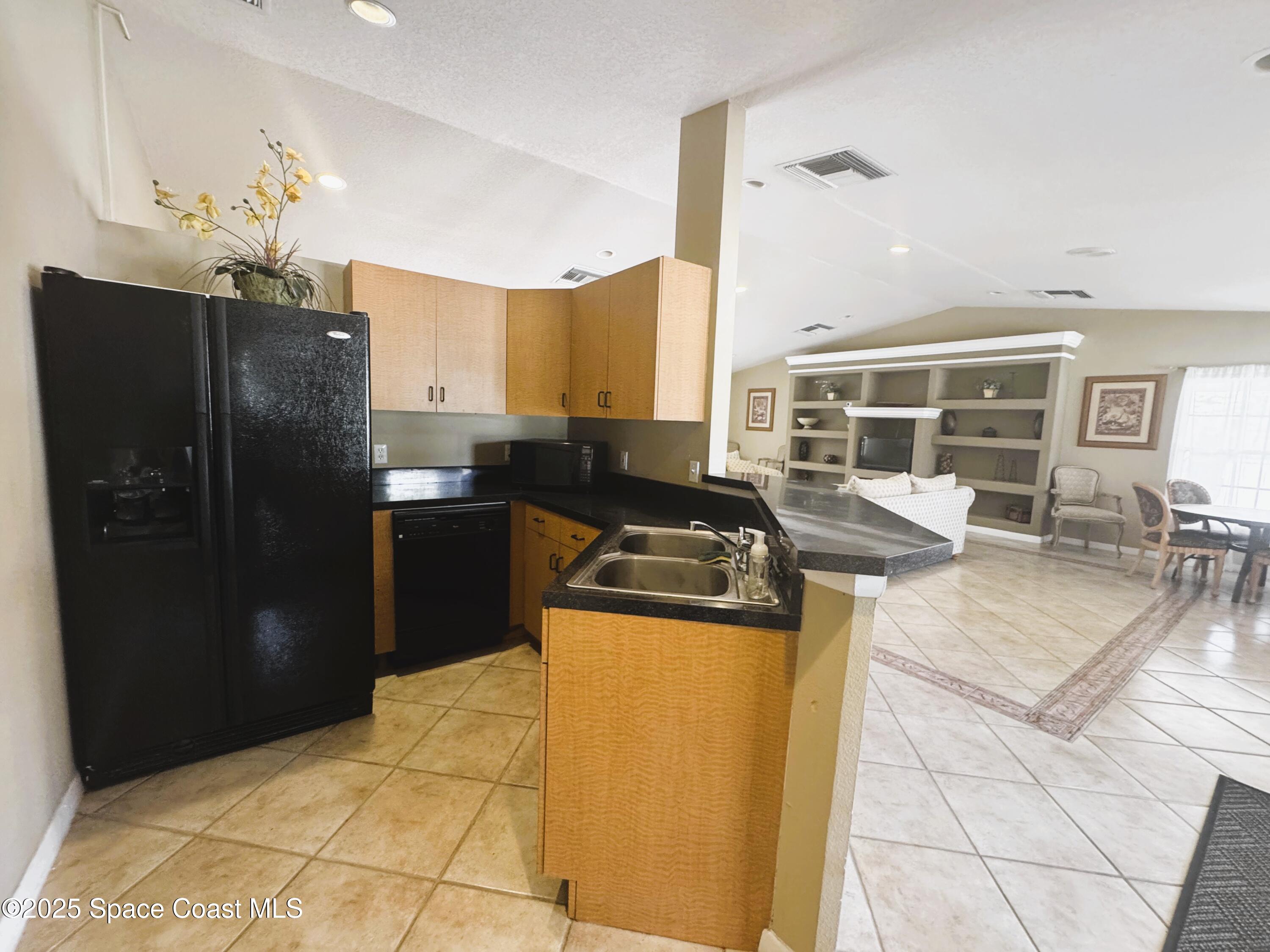 1861 Long Iron Drive, Unit 1121 Rockledge, FL 32955 - Photo 28 of 35 a kitchen with stainless steel appliances granite countertop a refrigerator a sink dishwasher a stove and a dining table with wooden floor