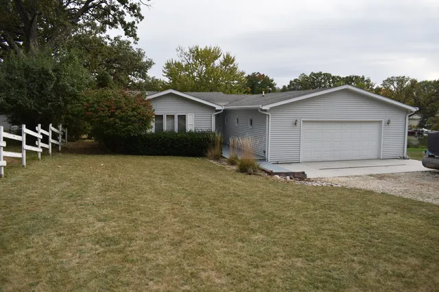 a backyard of a house with plants and large tree