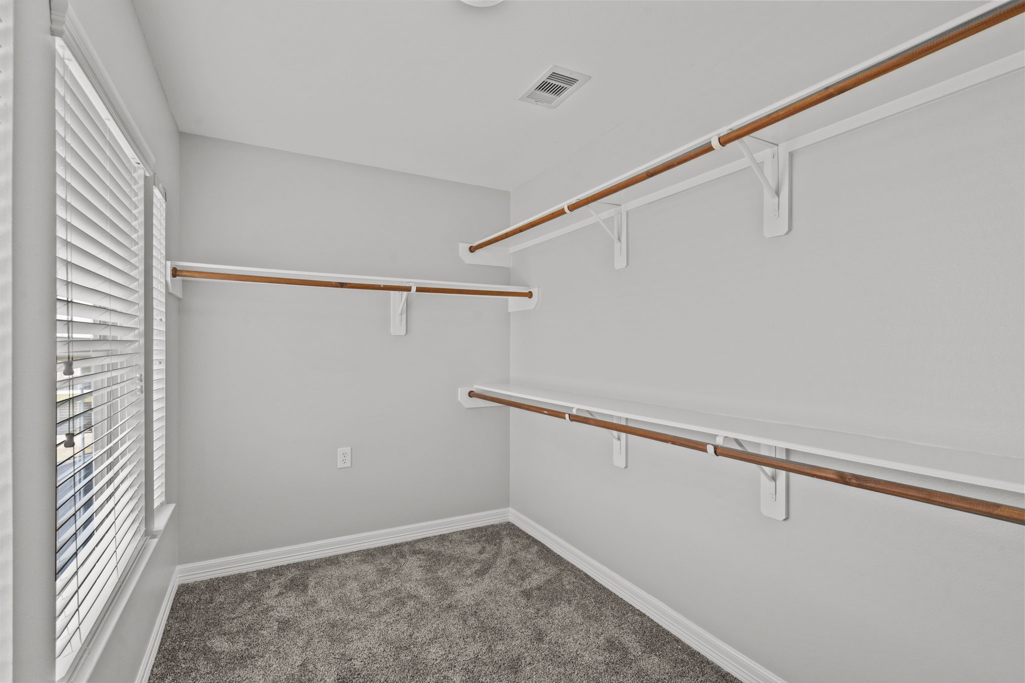 2730 Lawrence Road Kemah, TX 77565 - Photo 36 of 46 Spacious walk-in closet with ample shelving and hanging space, featuring a carpeted floor and a large window for natural light.