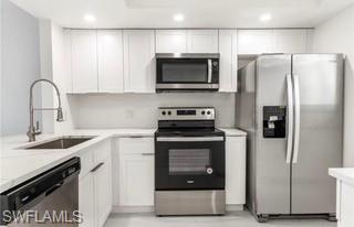 Kitchen with stainless steel appliances, light countertops, white cabinets, a peninsula, and recessed lighting