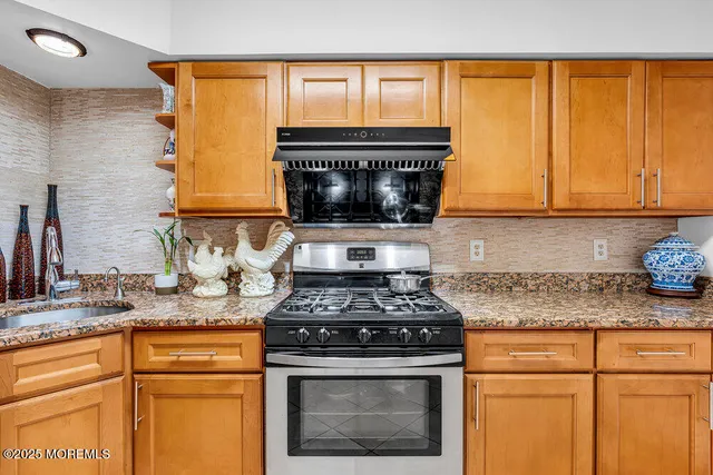 a kitchen with granite countertop a stove a sink and a microwave