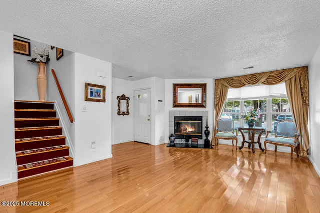 a view of a livingroom with furniture staircase fire place and windows