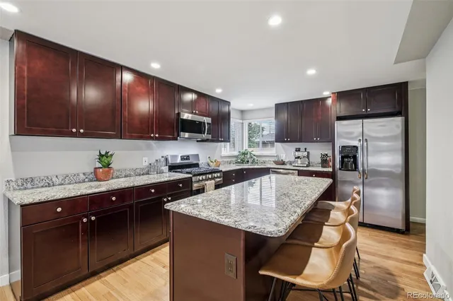 a kitchen with kitchen island granite countertop wooden cabinets a refrigerator a stove a sink and a oven