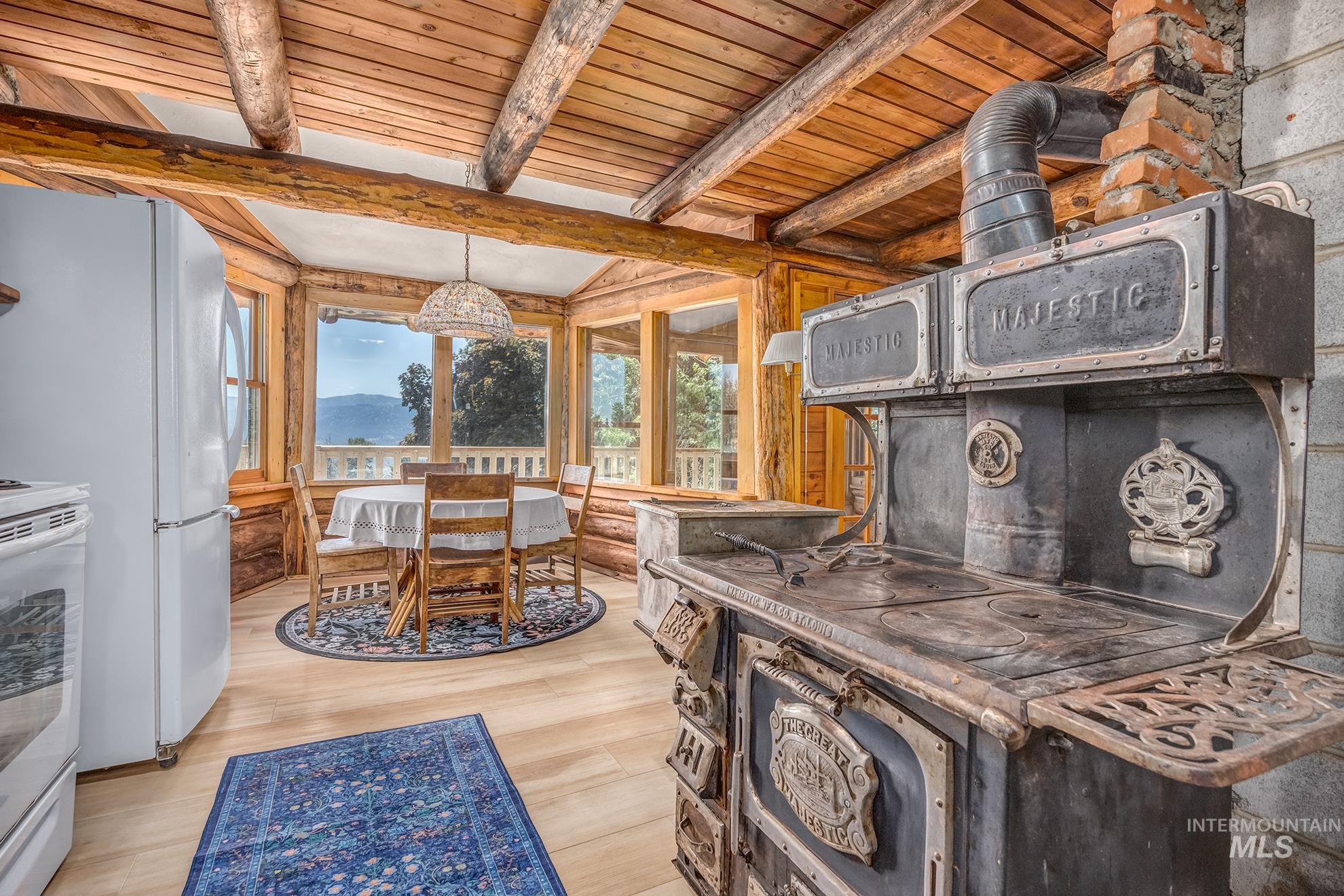 2150 Seid Creek Road Cambridge, ID 83610 - Photo 8 of 50 Kitchen area featuring a vintage-style range with brick chimney, exposed wood beam ceiling, wood-finish flooring, and a dining nook with panoramic windows