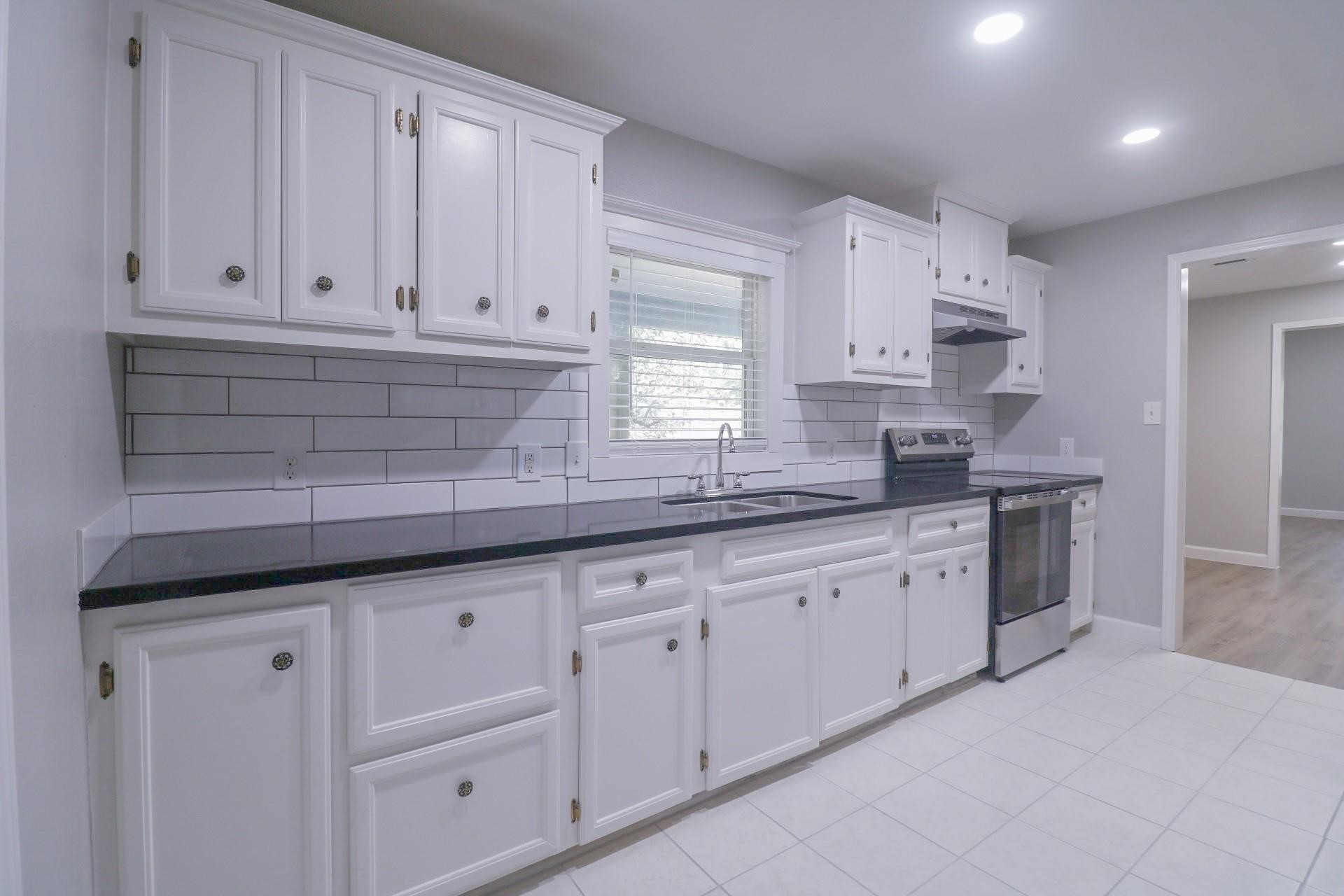 6150 Ridgeway Drive Houston, TX 77033 - Photo 12 of 36 a kitchen with granite countertop white cabinets and sink