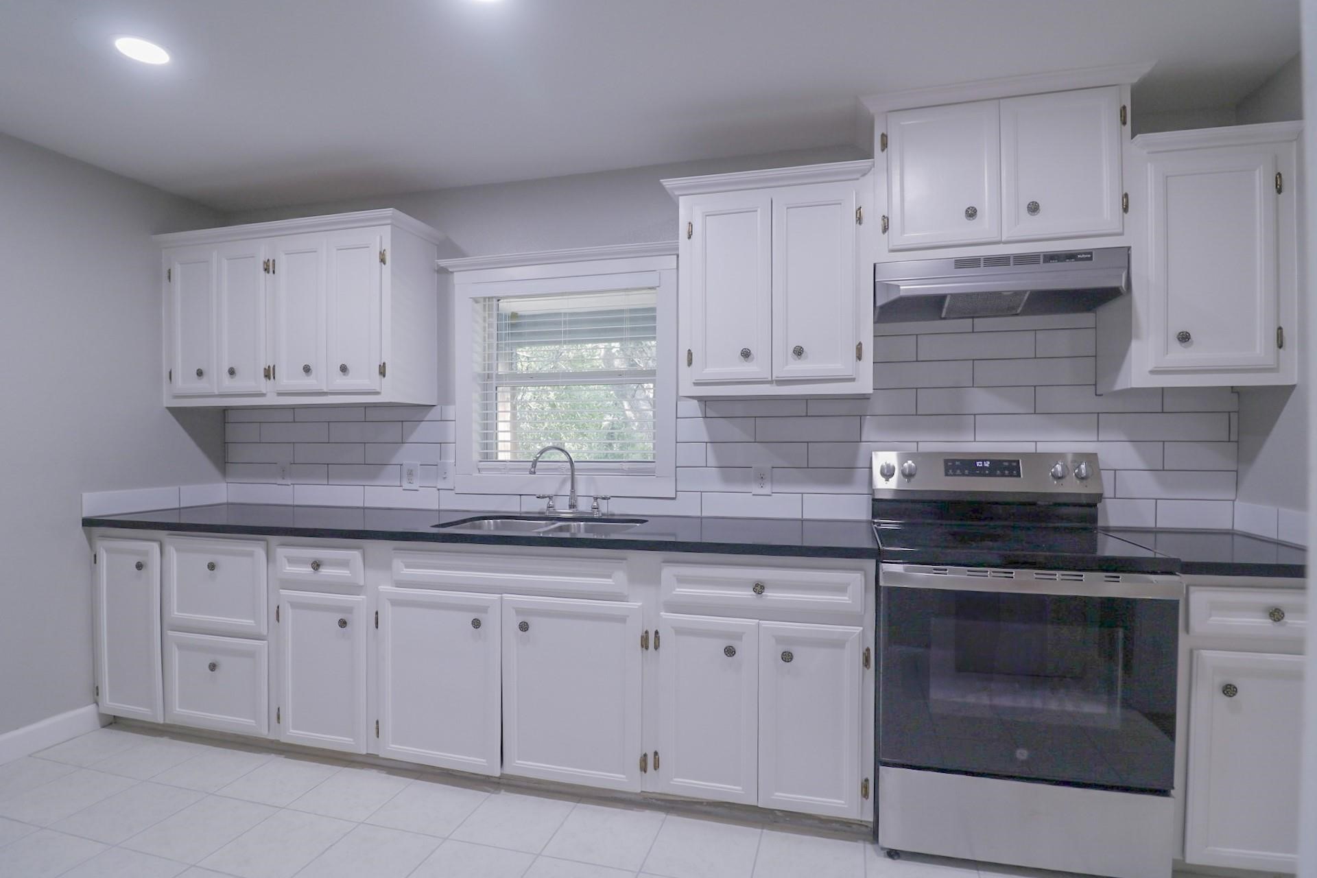 6150 Ridgeway Drive Houston, TX 77033 - Photo 13 of 36 a kitchen with white cabinets stainless steel appliances and a sink