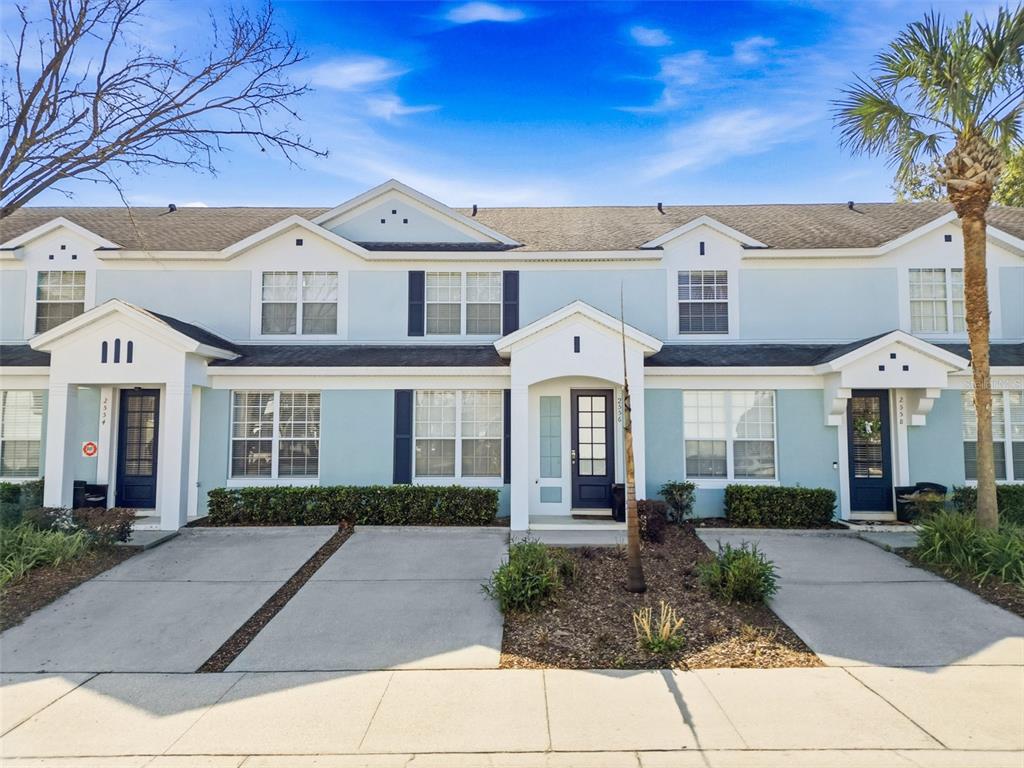 a view of a white house with large windows and a small yard