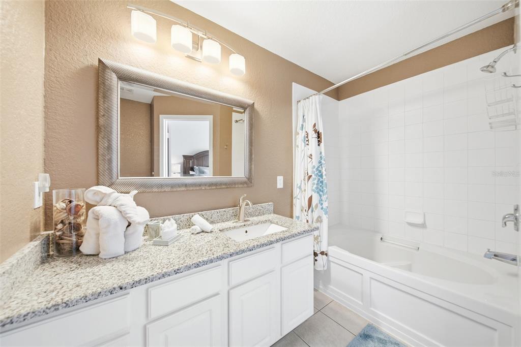 2556 Renshaw Street Kissimmee, FL 34747 - Photo 19 of 26 a bathroom with a granite countertop sink mirror and a bathtub