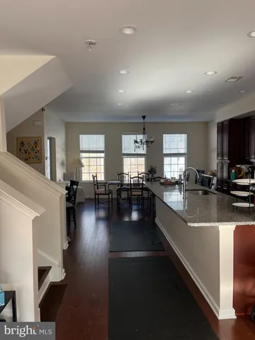 a large white kitchen with granite countertop lots of counter top space a sink and stainless steel appliances
