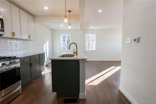 a kitchen with granite countertop a stove a sink and a refrigerator