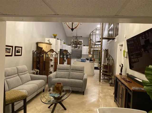 a living room with furniture a flat screen tv and floor to ceiling window