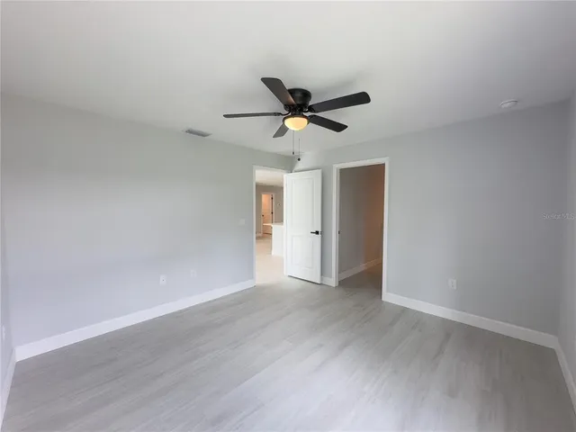 a view of a room with wooden floor and a ceiling fan