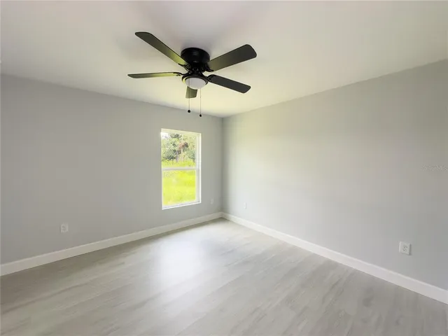 an empty room with a window and a ceiling fan