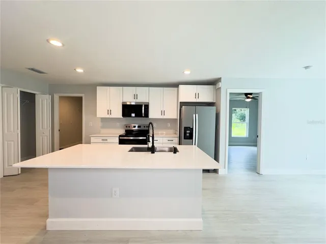 a large kitchen with stainless steel appliances kitchen island a stove a refrigerator a sink dishwasher with a dining table and chairs