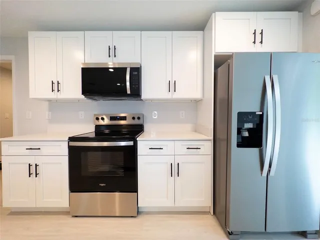a kitchen with stainless steel appliances a refrigerator stove and white cabinets