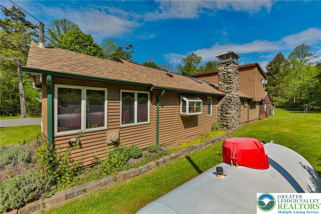 331 Cranberry Creek Road Cresco, PA 18326 - Photo 89 of 95 A spacious home with wood siding and a stone chimney, set against a verdant landscape.