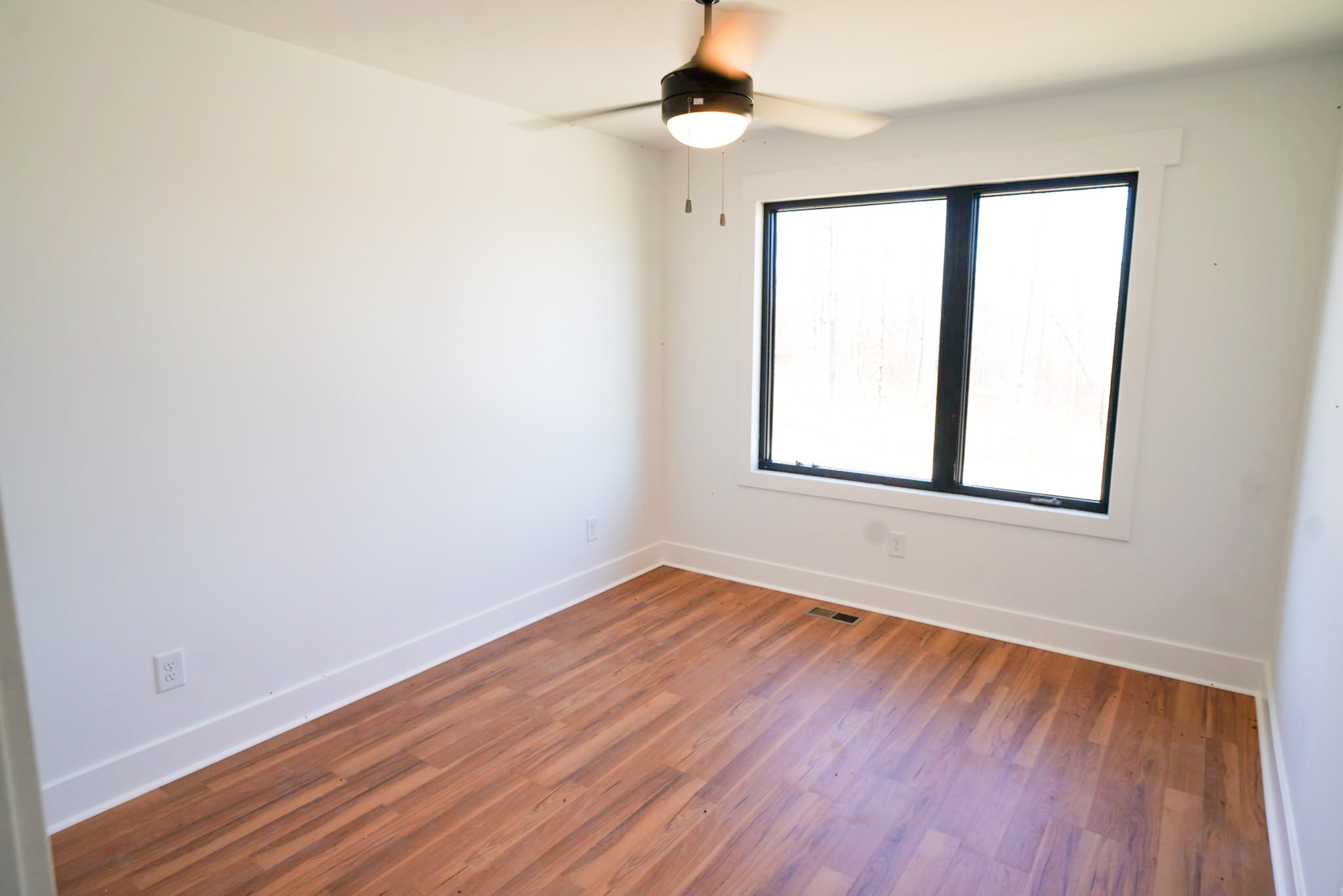 943 Overlook Trail Stewart, TN 37175 - Photo 22 of 35 an empty room with wooden floor chandelier fan and windows