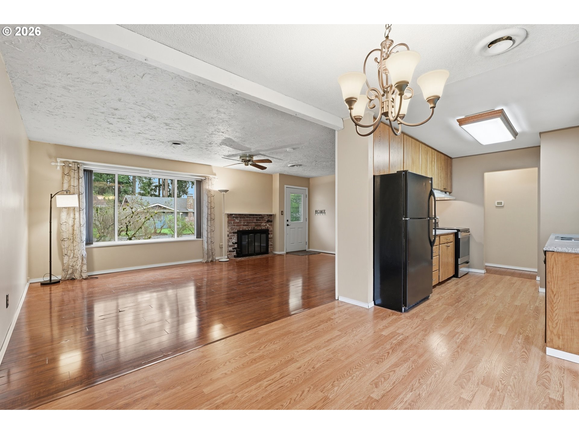 335 Southwest 141st Avenue Beaverton, OR 97006 - Photo 10 of 42 a view of an empty room with wooden floor and a kitchen