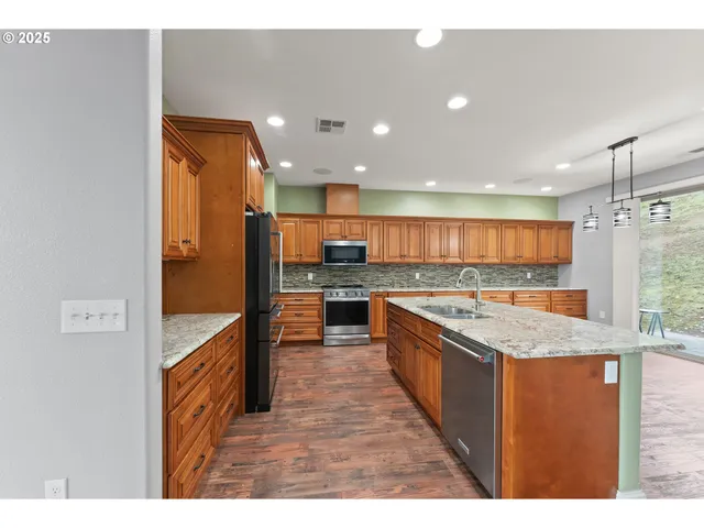 a kitchen with stainless steel appliances granite countertop a sink and a refrigerator
