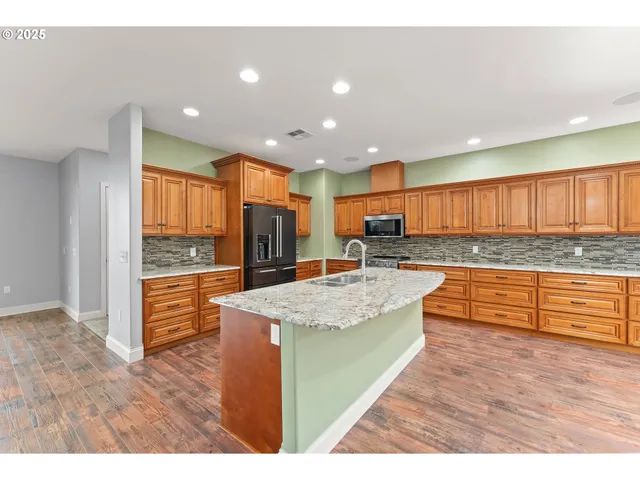 a large kitchen with granite countertop a large counter top stainless steel appliances and cabinets