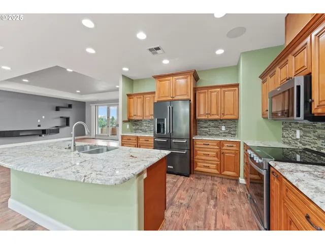 a kitchen with stainless steel appliances granite countertop a sink refrigerator and cabinets