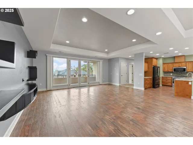 a view of an empty room with a window and wooden floor
