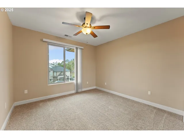 a view of an empty room with chandelier fan and fire place
