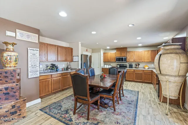 a kitchen with stainless steel appliances granite countertop wooden cabinets a sink dishwasher a stove and a refrigerator with wooden floor