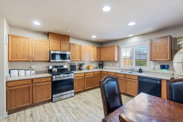 a kitchen with stainless steel appliances granite countertop a refrigerator a sink dishwasher a stove top oven a refrigerator with wooden floor and cabinets