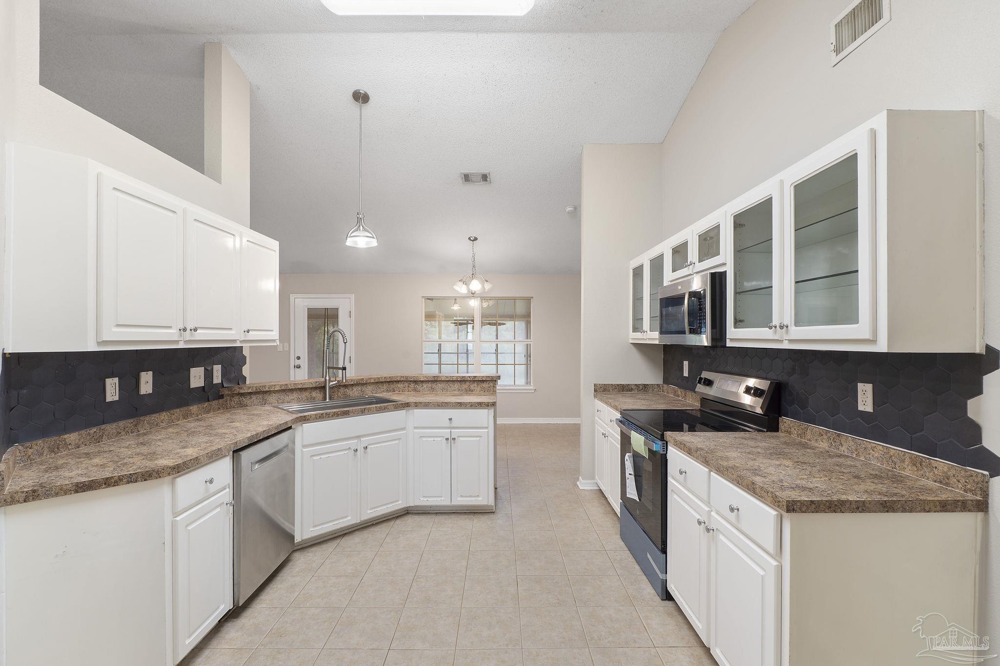 5642 Berrybrook Circle Pace, FL 32571 - Photo 12 of 72 a kitchen with stainless steel appliances granite countertop a sink and stove top oven
