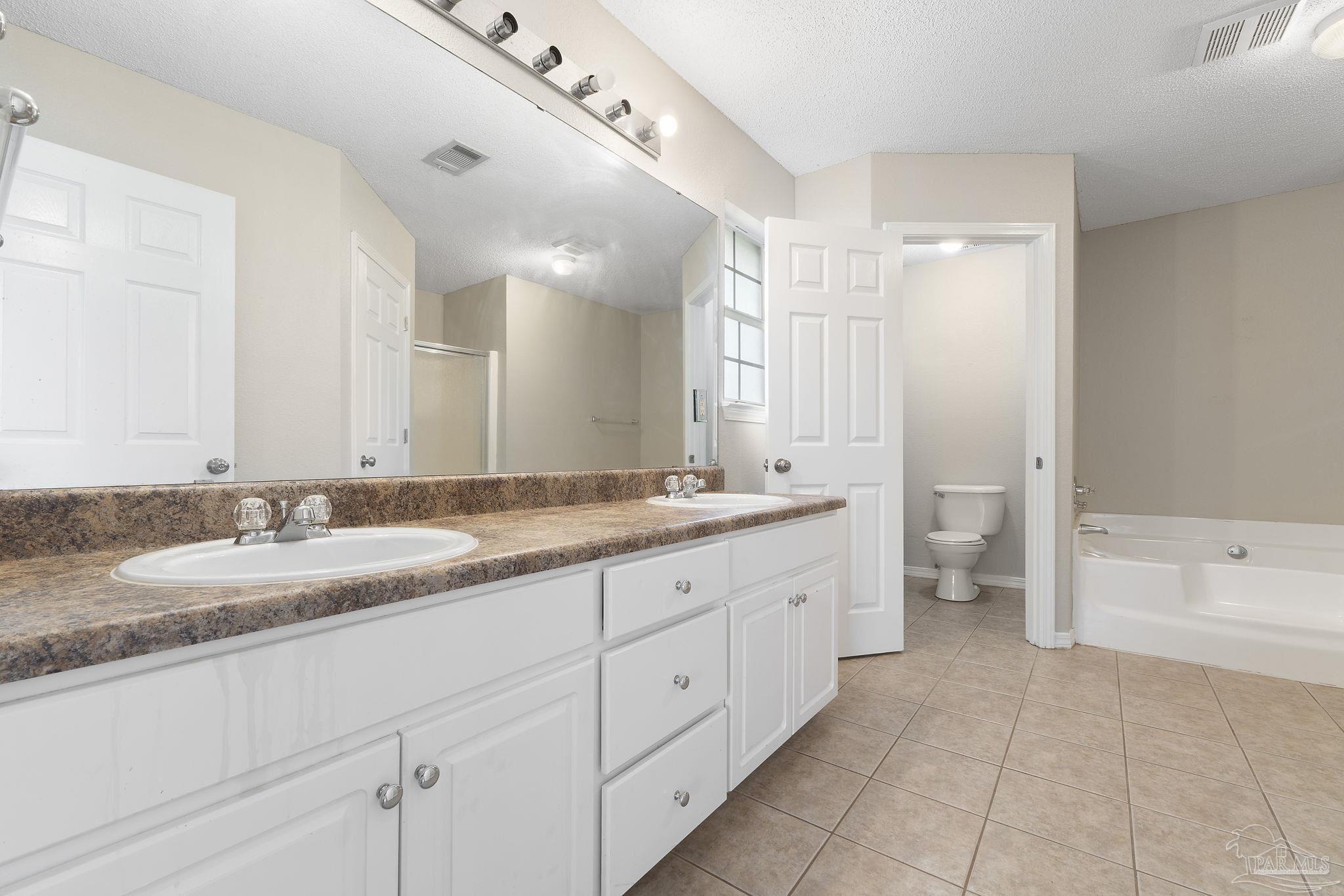 5642 Berrybrook Circle Pace, FL 32571 - Photo 19 of 72 a spacious bathroom with a granite countertop double vanity sink a mirror and a bathtub