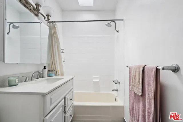 a bathroom with a sink vanity tub shower and a mirror