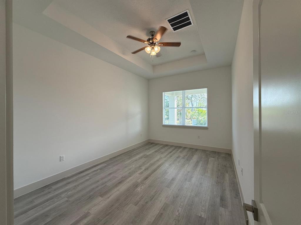 3057 Aliceville Road North Port, FL 34288 - Photo 23 of 33 an empty room with wooden floor chandelier fan and windows