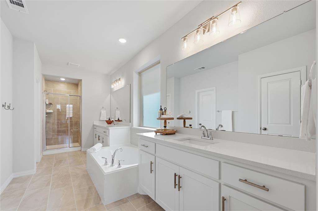 9317 Sunset Lane Oak Point, TX 75068 - Photo 15 of 40 a bathroom with double vanity sink a mirror and a bathtub